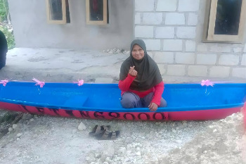 Mama Inang duduk di atas perahu bantuan dari alumni SMPN 1 Wabula angkatan 2000, yang kini menjadi harapan baru dalam menjalani aktivitas melaut.
